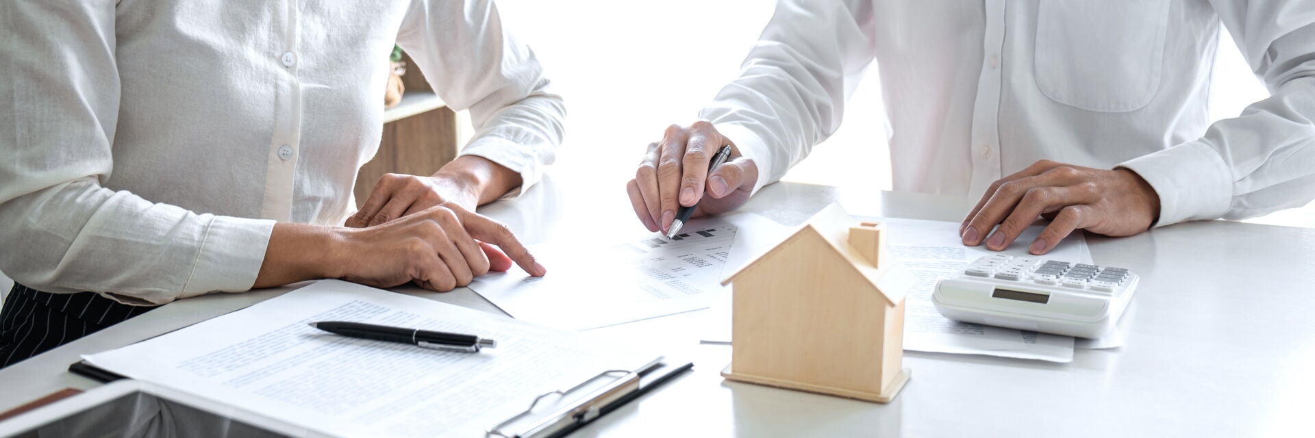 Immobilienvertragsunterzeichnung in Bautzen | Immobilien Anders GmbH Zwei Personen unterzeichnen einen Immobilienvertrag neben einem Holzhausmodell in Bautzen. Immobilien Anders GmbH – Ihr Partner vor Ort.